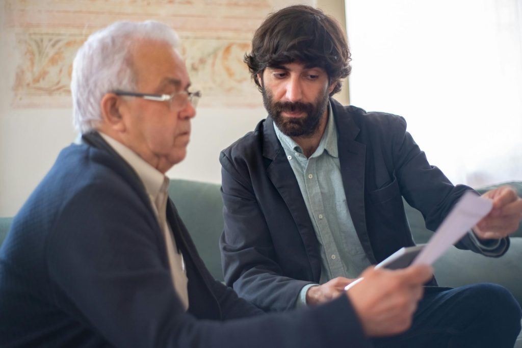 Two men engaged in a business consultation, reviewing documents in a professional setting.